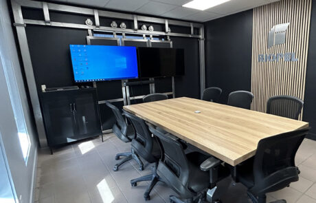 Photo d’une salle de conférence rénovée avec grande table en bois, chaises ergonomiques noires